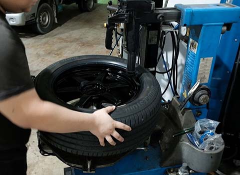 Picture of a KYC worker in the garage removing a tyre rim